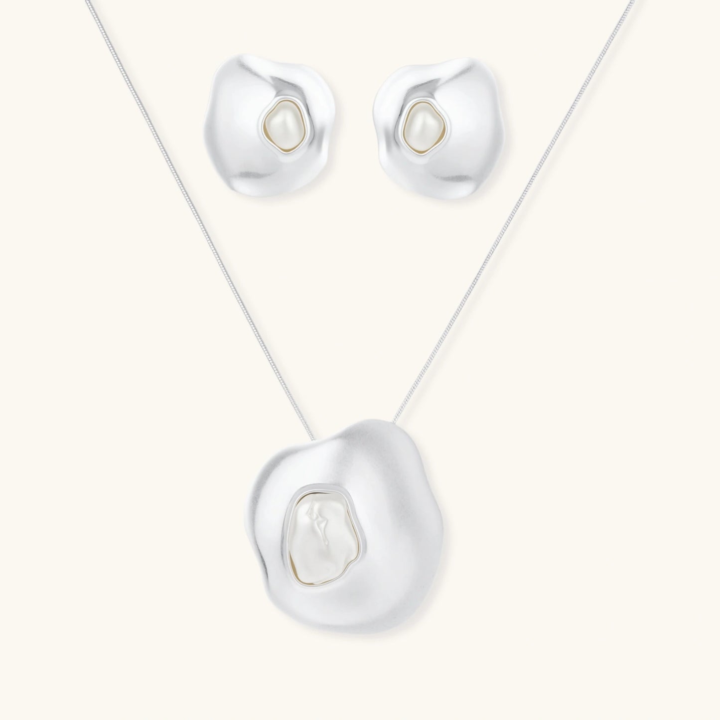 Organic curved earrings and necklace featuring baroque pearls in eco-zinc alloy settings on neutral background
