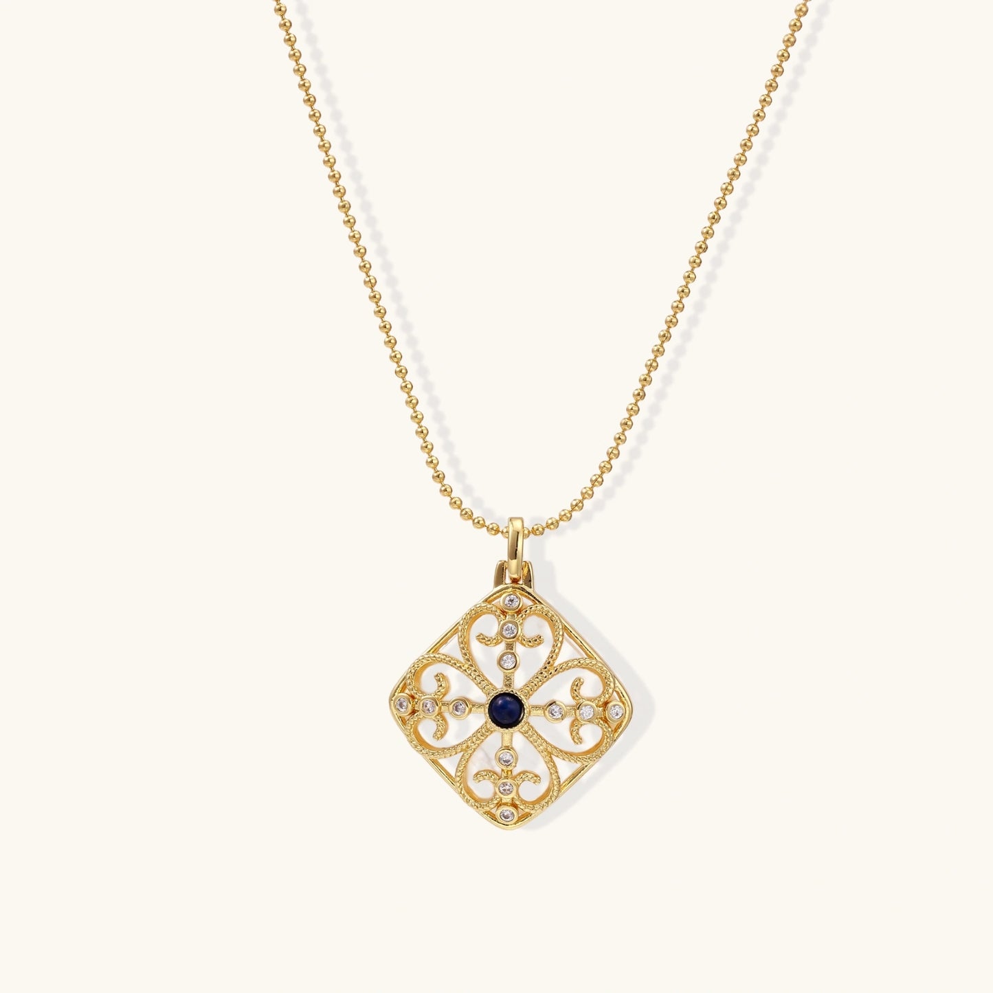 Gold filigree pendant with quatrefoil design, deep blue lapis lazuli center, clear crystal accents on ball chain